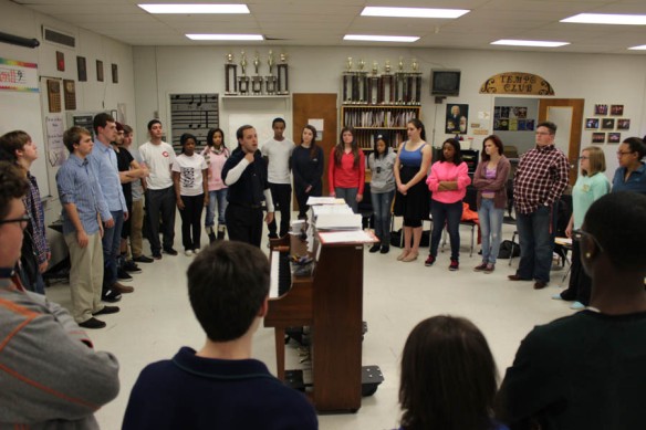 Steve Danielson leading a music rehearsal surrounded by the cast.